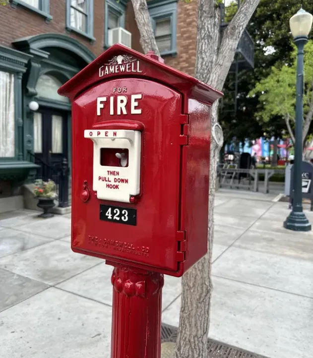 Red Gamewell fire alarm pull box on a city sidewalk
